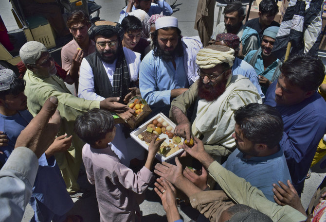 Leaders of the Pakistani religious group Jamiat Ulema-e Islam Nazryate party distribute sweets among people on a market area in Quetta, Pakistan, on Aug. 13, 2021, to celebrate the Taliban advance in Afghanistan. (AP Photo/Arshad Butt)