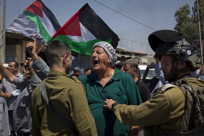 A Palestinian woman argues with Israeli soldiers during a protest against the creation of a new road for Israeli settlers near the village of Beita in the West Bank on Aug. 25, 2021. (AP Photo/Majdi Mohammed) 