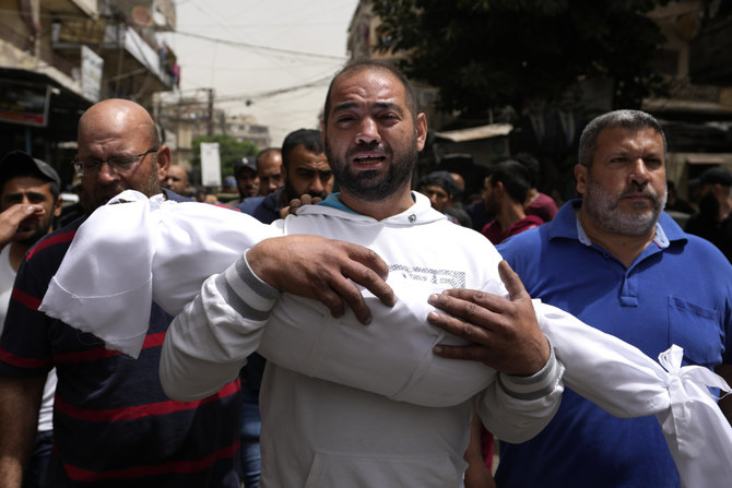 A man carries the body of a young girl during a funeral procession in Tripoli, Lebanon, for seven people killed when a boat pack