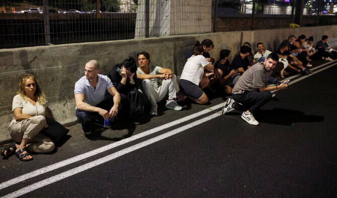 People take cover by the side of a road as a siren sound, after Iran fired a salvo of ballistic missiles. (Reuters)