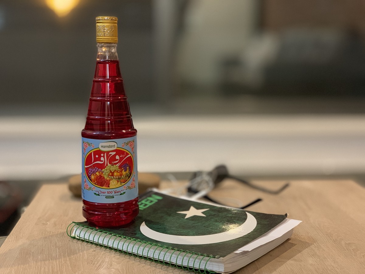 Rooh Afza, a rose-flavored concentrate of herbs, fruits, and flowers, is a staple of Ramadan in both Pakistan and India. In this photo taken on May 9, 2019, a bottle of Pakistani-produced Rooh Afza is seen on a table next to a notebook with a Pakistan flag cover. (AN Photo)